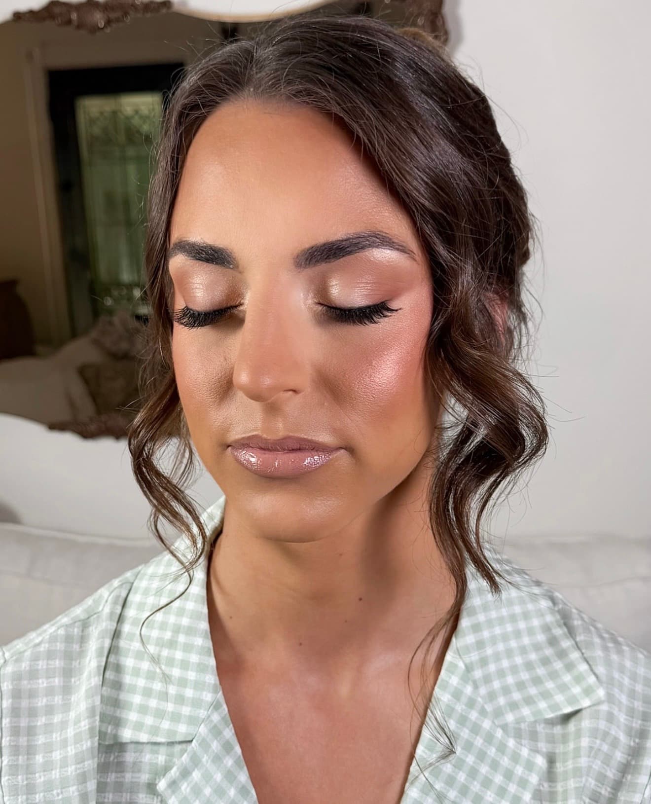 Bride with soft waves and romantic makeup featuring warm nude eyeshadow, defined lashes, and mauve-toned lips.